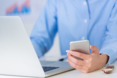 Online newsrooms image of person at laptop with phone