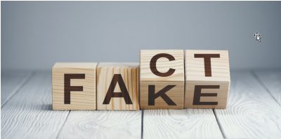 Wooden blocks spelling FACT and FAKE for AI and misinformation
